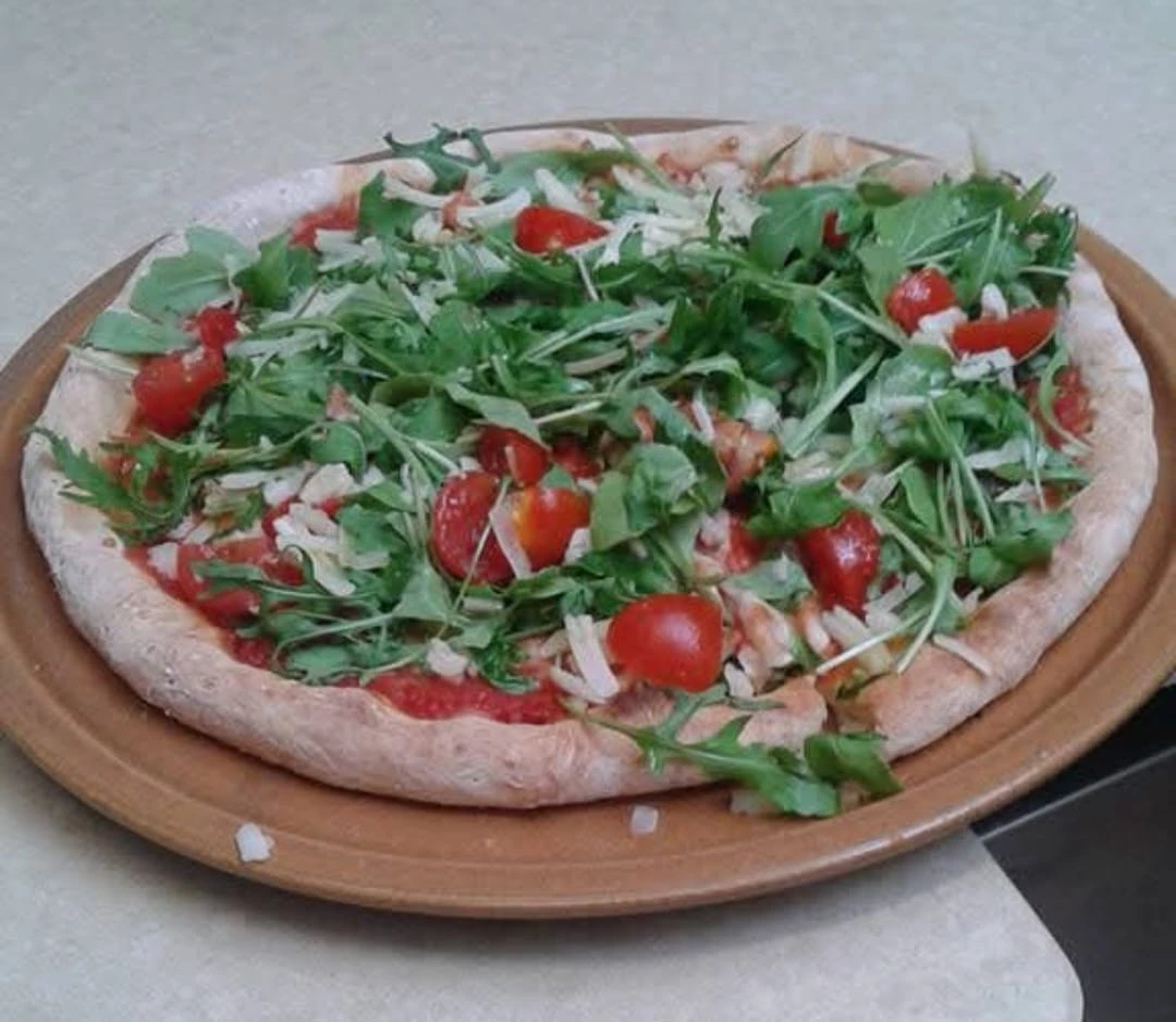 Pizza artigianale con rucola, pomodorini e grana
